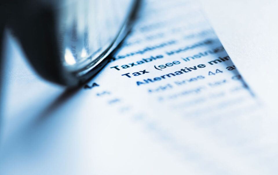 Document with the Word Tax on it with a pair of eyeglasses on top of it.