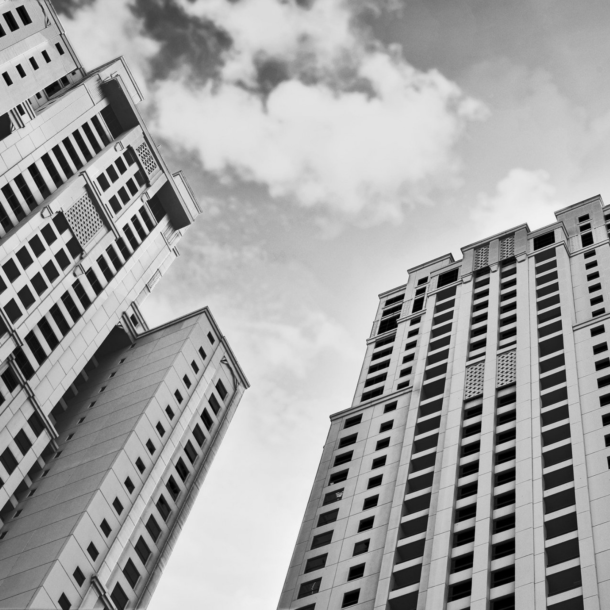 Black and white picture of tall apartment buildings with clouds