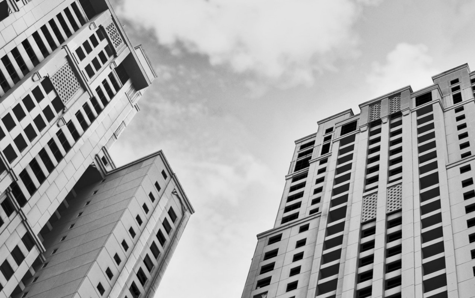 Black and white picture of tall apartment buildings with clouds