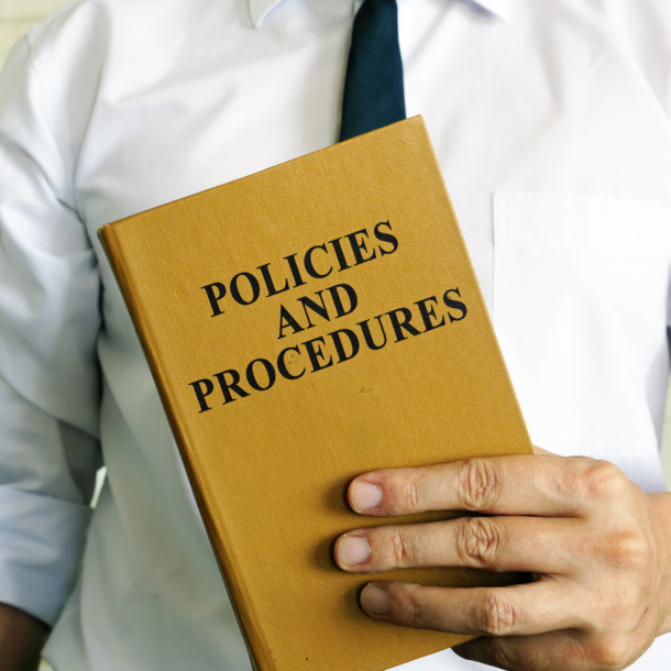 A man holding a yellow book titled Policies and Procedures