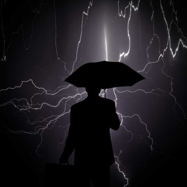 silhouette of businessman holding umbrella facing lightning storm