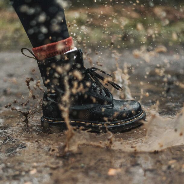 Person splashing in water wearing black boots