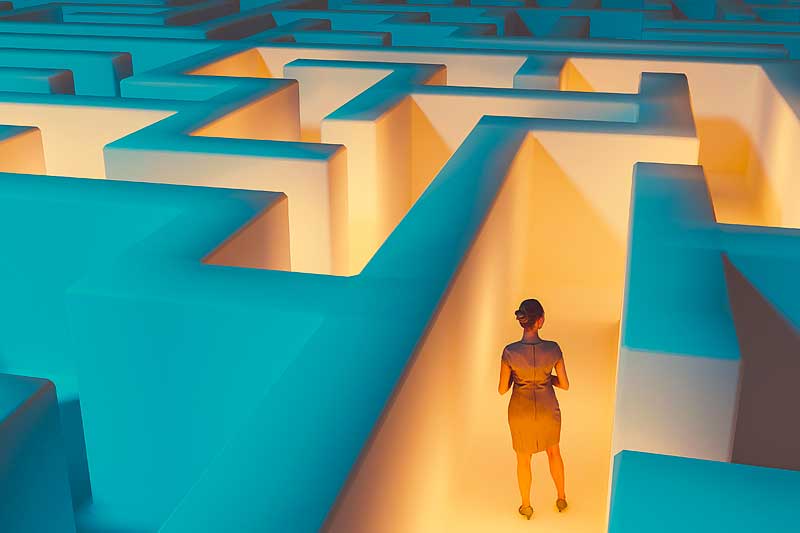 Woman stands in the middle of dark maze. Lights guide the way for her