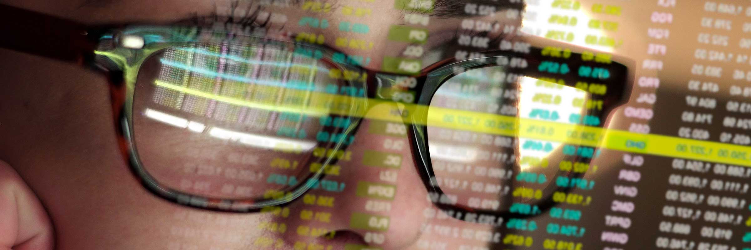 Woman reviewing financials with numbers reflecting in her glasses.