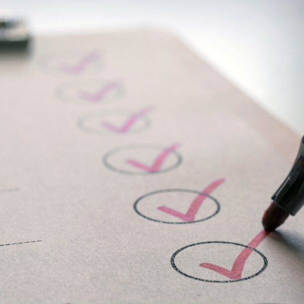 Close-up of a red highlighter marking check circles on a printed checklist, indicating completing tasks.