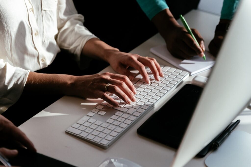 Top shot photo of an individual typing on the keyboard of a desktop computer