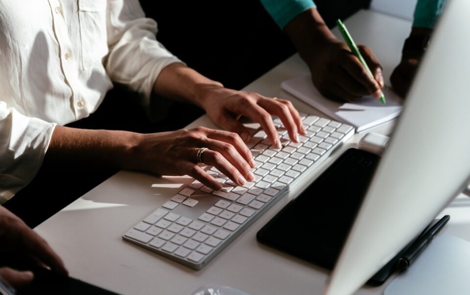 Top shot photo of an individual typing on the keyboard of a desktop computer