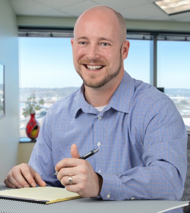 Photo of Jeff DeGree, CPA, Director on Mahoney's Real Estate Solutions Team smiling and sitting at a desk with a notebook and pen in hand.