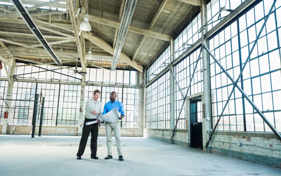 Photo of real estate developers reviewing blueprints within a partially developed commercial building.