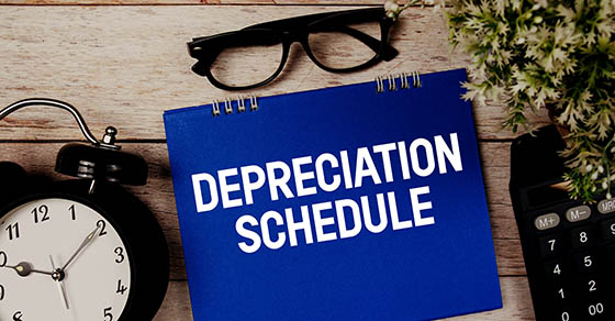 Depreciation Schedule text with alarm clock and calculator on wooden background