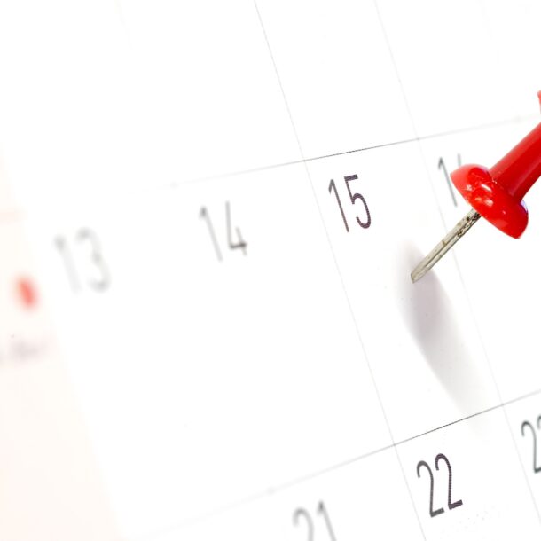 Focused image of a pushpin on the 15th day of a paper wall calendar.