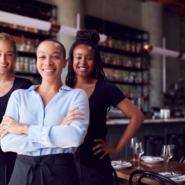 Image of three restaurant employees standing in front of the bar and smiling at the camera.