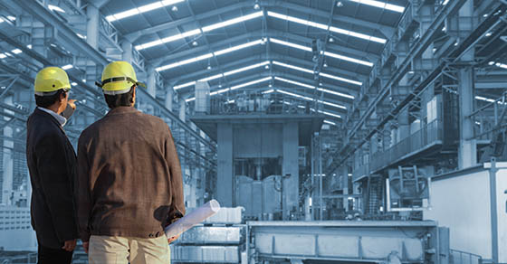 Photo of construction workers in hardhats in a warehouse in development.
