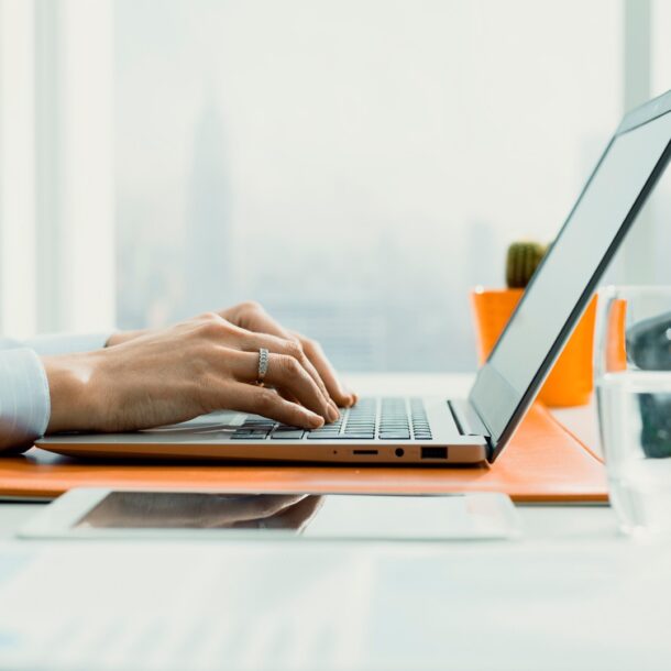 Medium shot from a side angle of a person typing on a laptop.