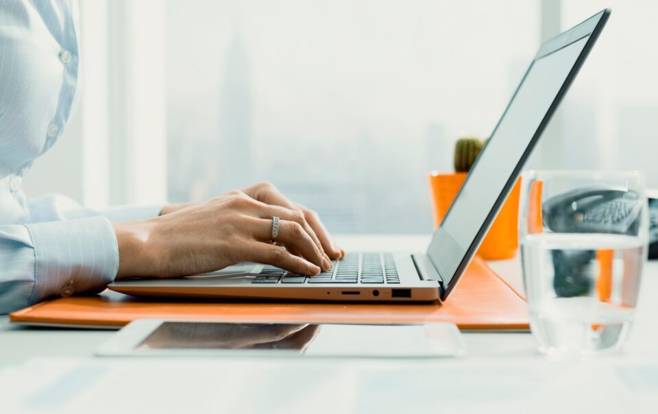 Medium shot from a side angle of a person typing on a laptop.
