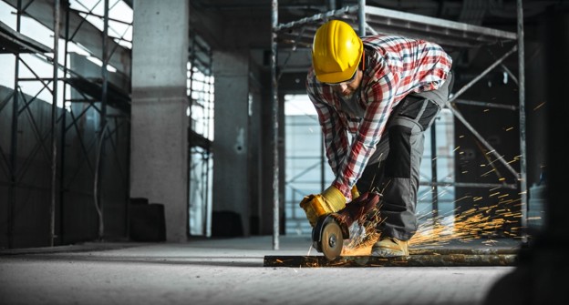 Photo of a construction worker using a saw on steel in a developing building.